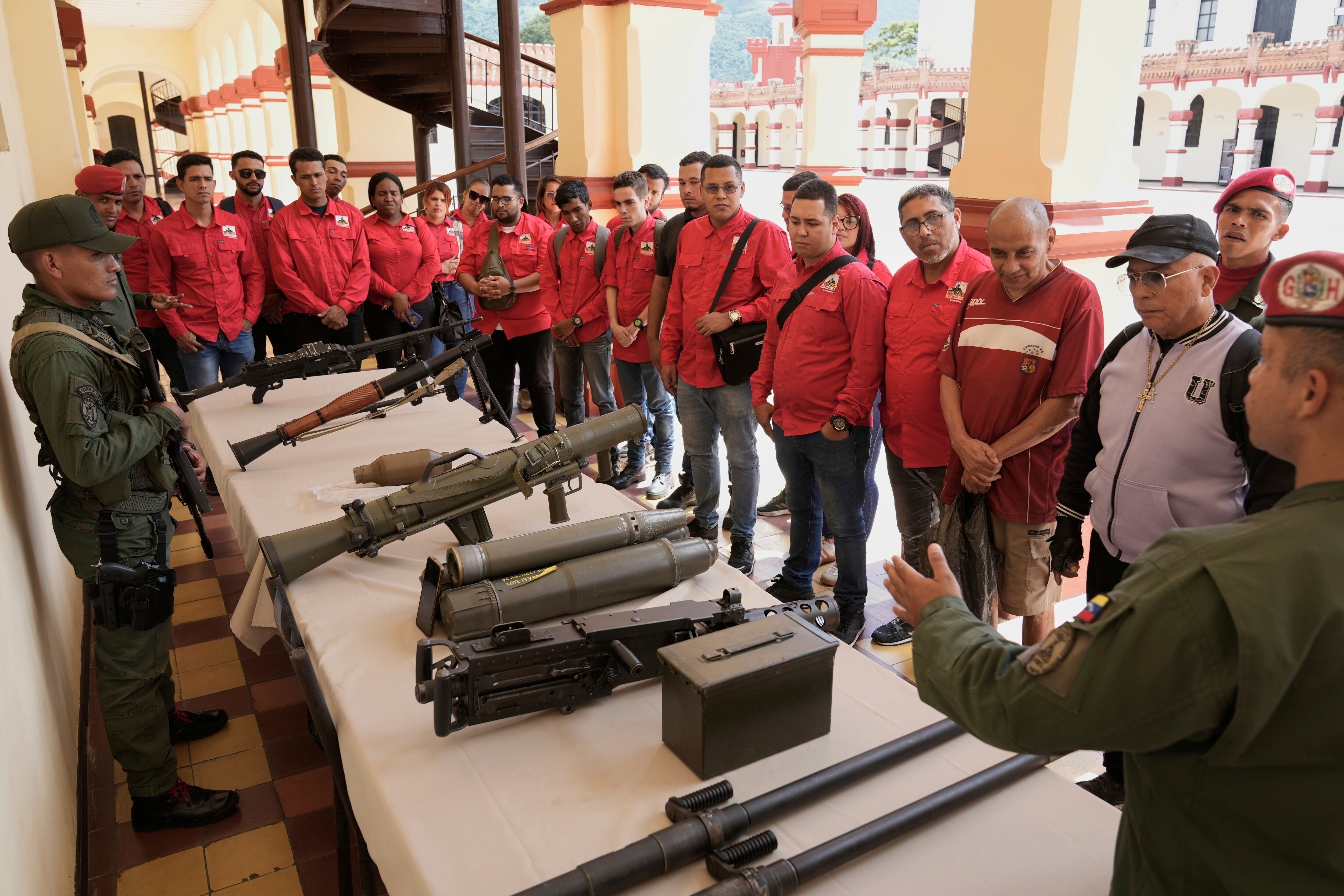 Un miembro de la guardia presidencial venezolana muestra armas a quienes se alistaron para unirse a las milicias civiles durante una campaña de Maduro, en el museo militar de Caracas, Venezuela, el sábado 23 de agosto de 2025 (AP Foto/Ariana Cubillos)