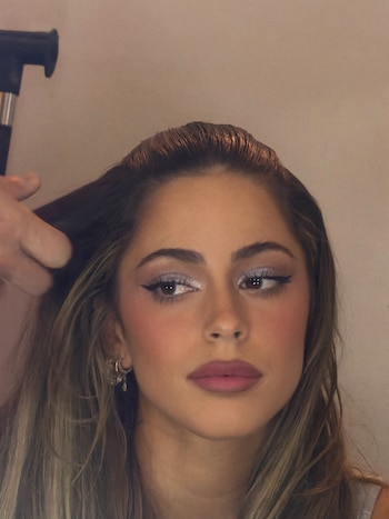 Rostro de Tini Stoessel con maquillaje de ojos y labios mientras una mano acomoda su cabello