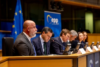 Una fila de hombres con traje sentados en una mesa con micrófonos. Detrás, una bandera de la Unión Europea y un banner azul con el logo EPP