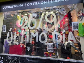 Fachada de vidrio de un local comercial con el texto 26/9 ÚLTIMO DÍA pintado en blanco y avisos de liquidación total