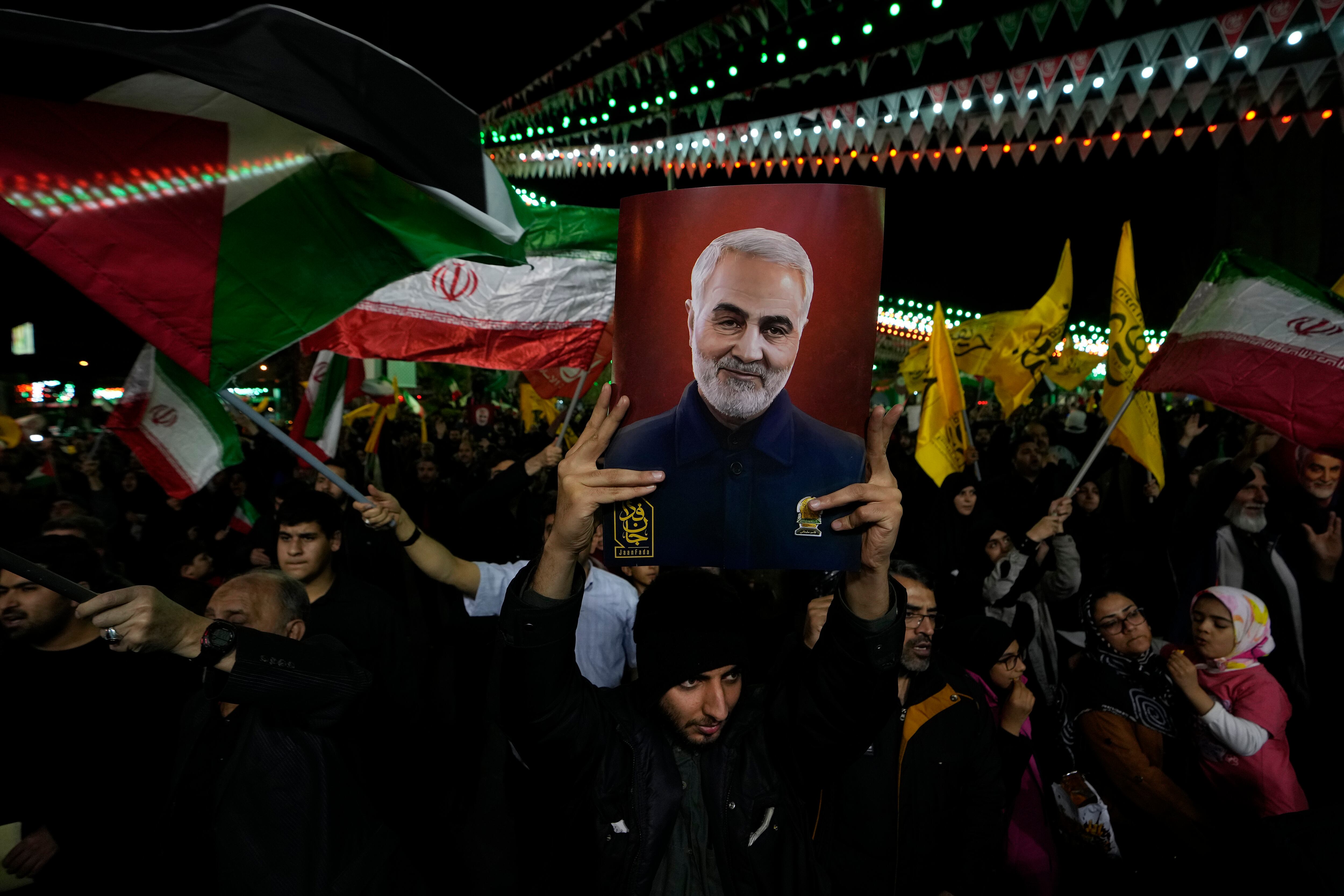 Manifestantes ondean banderas iraníes y palestinas mientras uno de ellos sostiene un cartel con al imagen del fallecido general de la Guardia Revolucionaria Iraní Qassem Soleimani. (AP Foto/Vahid Salemi)