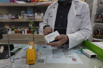 Un farmacéutico recorta el código de barras de una caja de Paracetamol en su farmacia.