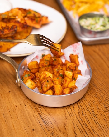 unas patatas cocinadas con especias servidas en una sartén pequeña en un restaurante