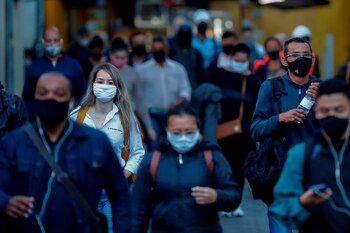 Personas con tapabocas caminan por