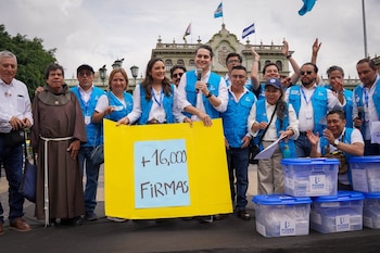 Una multitud con sombrillas y chalecos de Poder Ciudadano se reúne frente al Palacio Nacional de la Cultura bajo la bandera de Guatemala