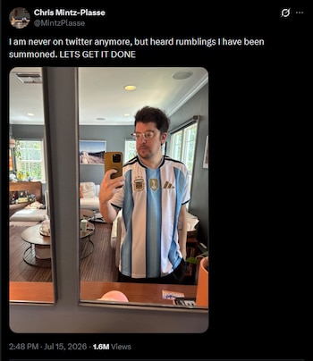 Hombre joven con anteojos y barba se toma una selfi frente a un espejo, viste una camiseta de fútbol a rayas celestes y blancas con el escudo de AFA