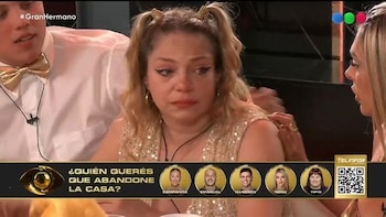 Mujer rubia con coletas y vestido brillante, rostro con lágrimas. Dos personas. Barra gráfica con pregunta de votación, retratos y código QR. Texto '#GranHermano'