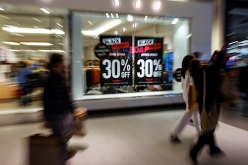 Shoppers walk by advertisements at