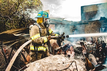 Bombero realizó labores de enfriamiento tras el incendio que destruyó parte de una vivienda en El Salvador (Cortesía: Cuerpo de Bomberos).