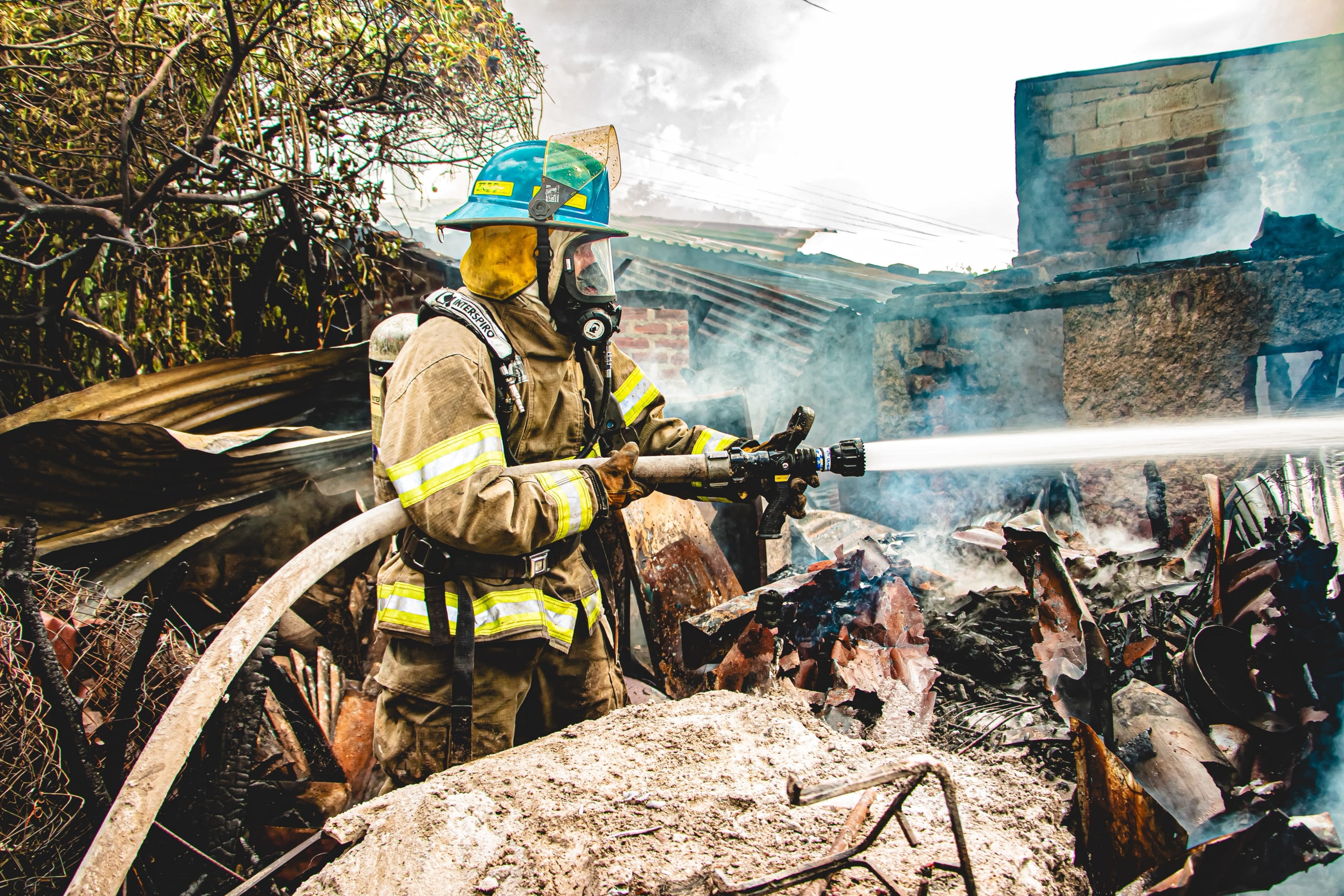 Bombero realizó labores de enfriamiento tras el incendio que destruyó parte de una vivienda en El Salvador (Cortesía: Cuerpo de Bomberos).