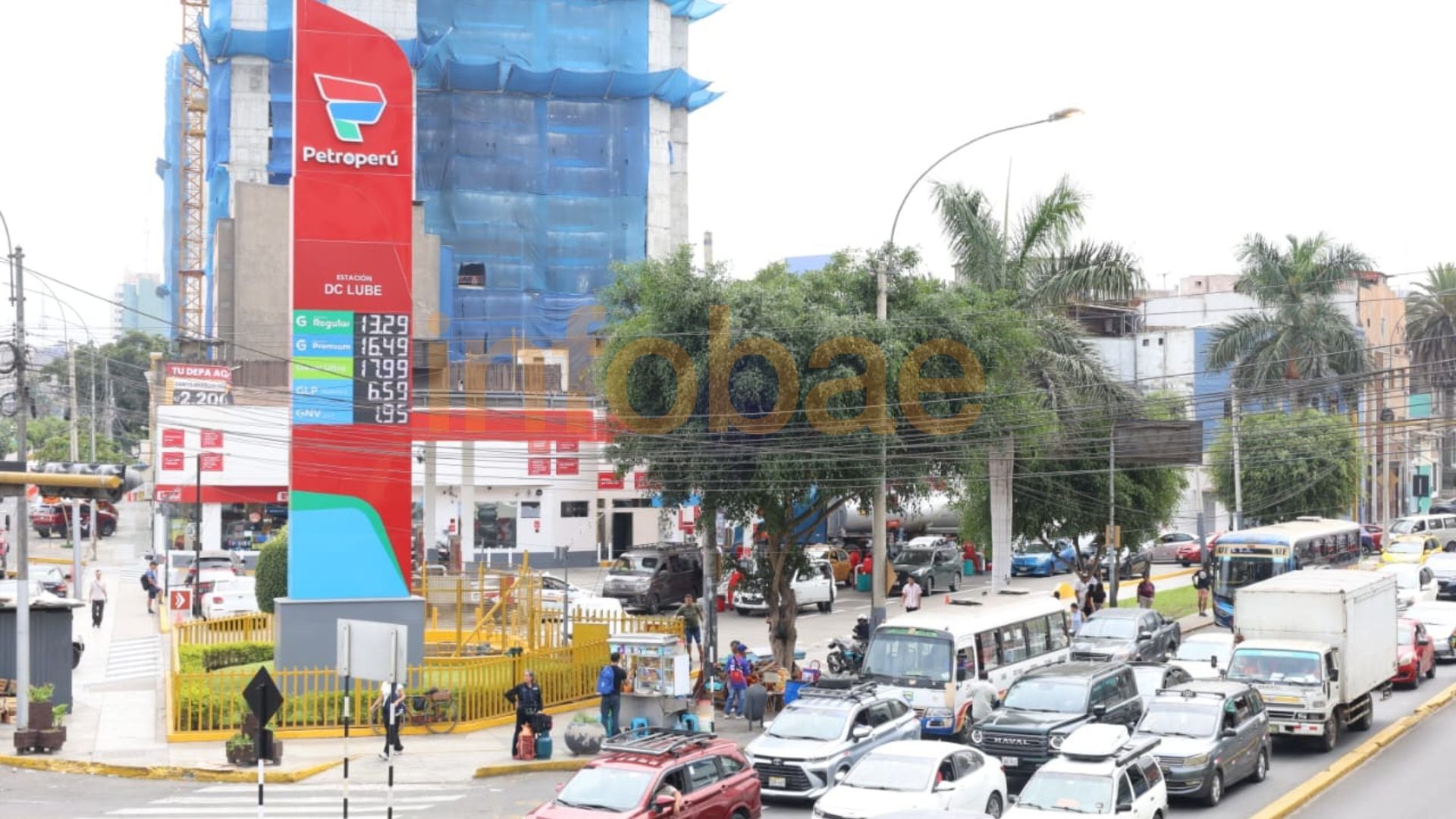 Una estación de servicio Petroperú con sus precios de combustibles visiblemente exhibidos, enmarcada por el intenso tráfico urbano que incluye SUVs, coches compactos y autobuses. (Paula Elizalde / Infobae Perú)