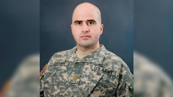 Retrato de un hombre calvo con uniforme militar de camuflaje que lleva las etiquetas Hasan y U.S. Army sobre un fondo oscuro