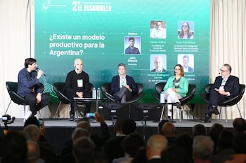 Panel con cinco personas, tres hombres y dos mujeres, sentados en sillas negras frente a una pantalla verde con el logo del '2º Congreso Productivo'. Una audiencia difusa en primer plano