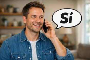 Hombre caucásico sonriente en primer plano hablando por un teléfono móvil, con una burbuja de texto blanco con la palabra 'Sí' en negro a su derecha.