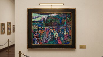Cuadro enmarcado con un paisaje colorido de figuras y un castillo, colgado en una pared clara junto a una placa e iluminación superior.