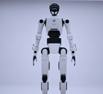 Robot humanoide blanco y negro de pie con brazos y piernas articulados sobre un fondo claro