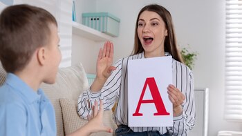 Una logopeda practica el sonido 'A' con un niño. (Canva)