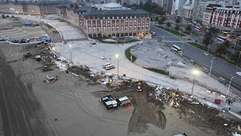 Vista aérea de una playa arenosa con maquinaria pesada y escombros. Junto a ella, un paseo, grandes edificios y una carretera con vehículos en movimiento