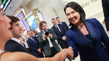 Keiko Fujimori sonríe y da la mano a una persona en la Bolsa de Valores de Nueva York rodeada de asistentes