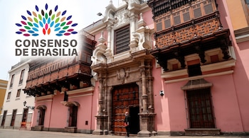 Fachada rosa de un edificio colonial con balcones de madera, portada de piedra y el logotipo del Consenso de Brasilia en la esquina superior.