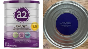 Primer plano de una lata de fórmula infantil a2 Platinum plateada y morada para 0-12 meses, junto a su tapa con detalles de lote y fecha de caducidad