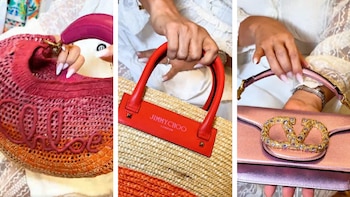 Primer plano de una persona mostrando tres carteras de diseñador: una Chloé de rafia degradada, una Jimmy Choo de rafia con asas rojas y un clutch Valentino rosa