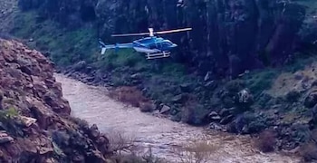 Dos personas observan una carpa médica inflable, una ambulancia y camionetas policiales en un terreno rural