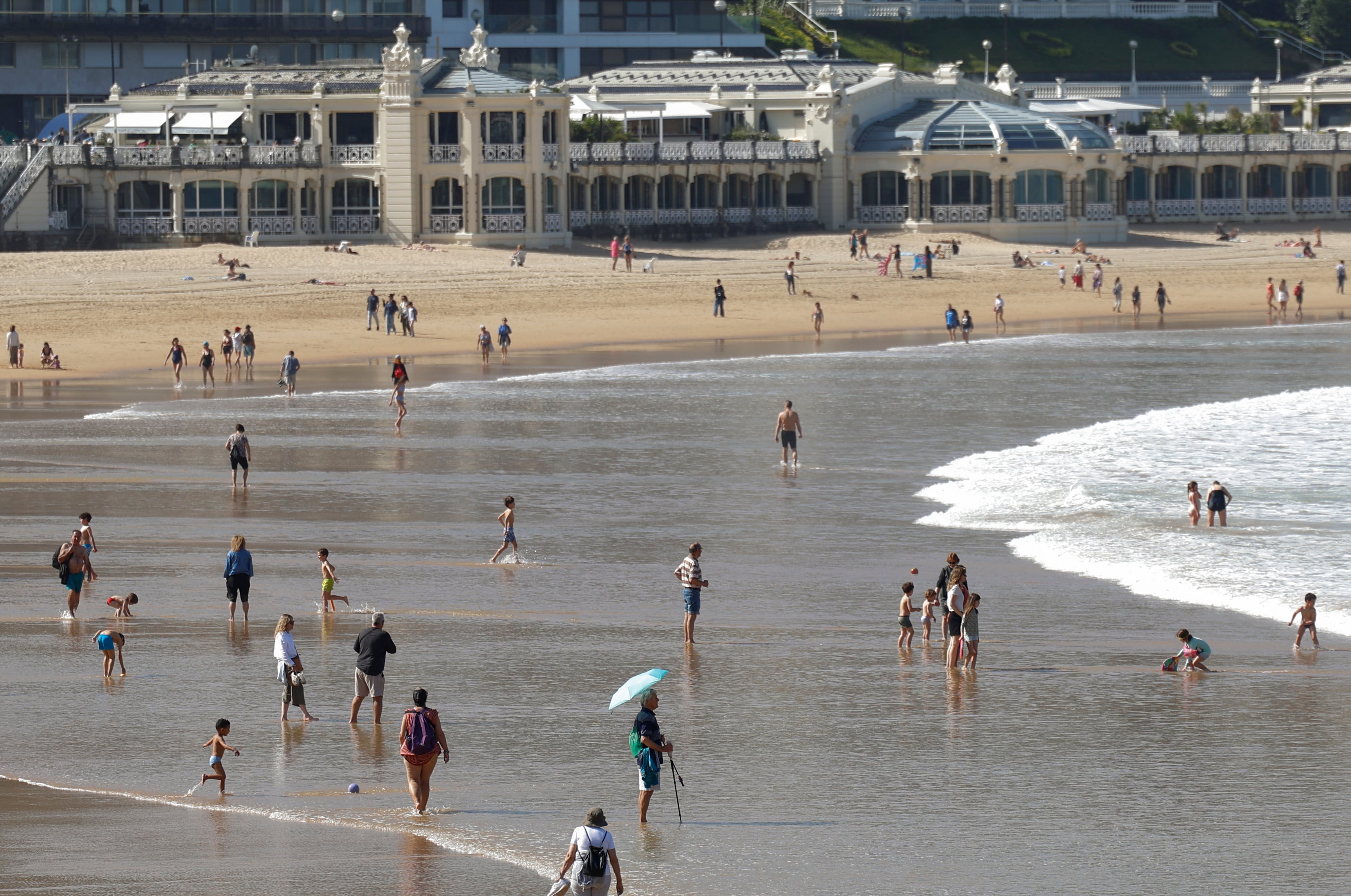 Bañistas disfrutan de un día soleado en la playa de la Concha de San Sebastián. (Juan Herrero/EFE)