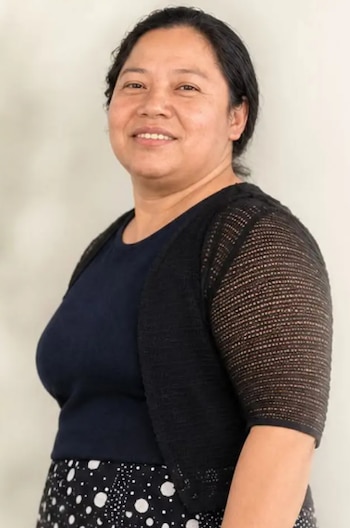 Retrato de medio cuerpo de una mujer con cabello oscuro, blusa azul, chaleco negro de tejido calado y prenda a lunares