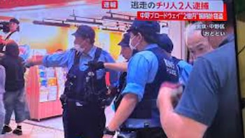 Varios agentes de policía en Japón con chalecos azules y mascarillas permanecen en un pasillo comercial