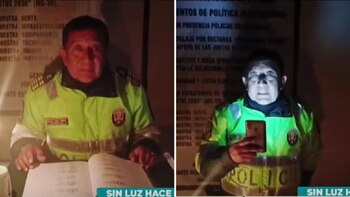 Policía alumbra con su celular para poder atender a un ciudadano.