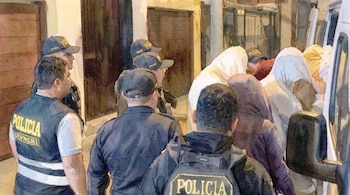 Ilustración en acuarela de agentes de policía con chalecos que escoltan a varias personas encapuchadas hacia un vehículo.