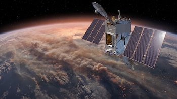 Un satélite metálico con paneles solares abiertos sobrevuela la Tierra, donde se observan gruesas nubes de humo e incendios en la superficie.