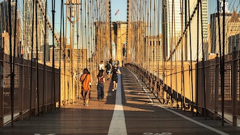 Peatones y corredores atraviesan la pasarela elevada del Puente de Brooklyn, una de las rutas más transitadas de Nueva York. La infraestructura no solo conecta Manhattan y Brooklyn, sino que también se convierte en el centro de nuevas propuestas para optimizar el uso del espacio urbano y sus áreas subutilizadas.