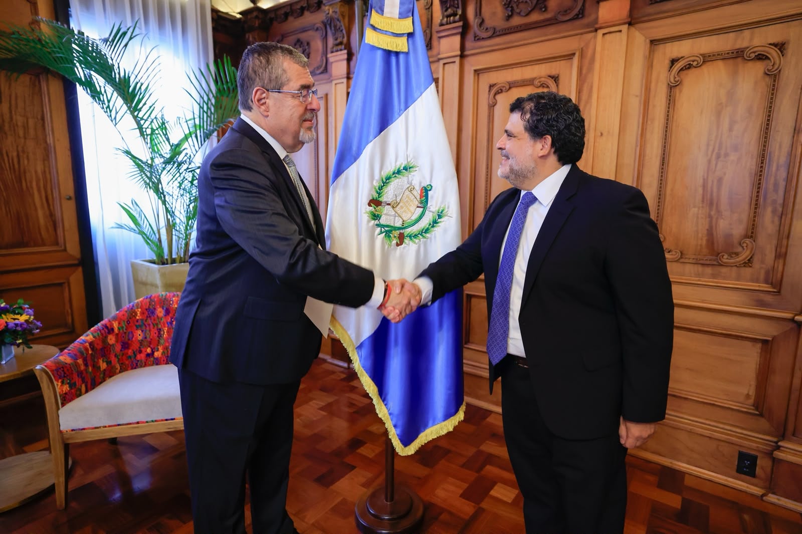 El presidente Bernardo Arévalo saluda a un representante durante un encuentro oficial frente a la bandera de Guatemala. (Secretaría de Comunicación Social de la Presidencia de Guatemala)