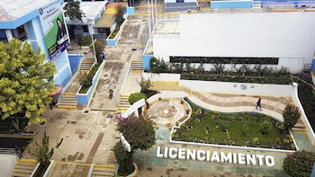 Vista aérea de campus universitario con edificios azules, jardines, escaleras y rampas. Letras 3D 'LICENCIAMIENTO'. Banner de Universidad Tecnológica de los Andes