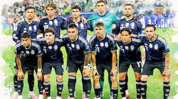 Ilustración en acuarela de once futbolistas varones en uniforme de la selección argentina posando en un campo de juego con público borroso al fondo.
