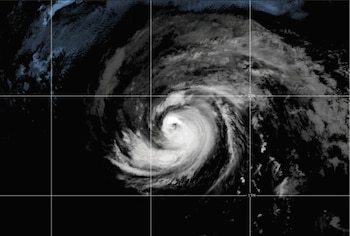 Imagen satelital en tonos grises de un ciclón tropical con un ojo central. El fondo oscuro incluye líneas de cuadrícula y etiquetas 20N y 15N