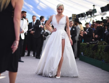 El vestido blanco de escote profundo y bordes deshilachados aportó frescura y modernidad al estilo de Lady Gaga en los Screen Actors Guild Awards (Photo by Robyn Beck / AFP)
