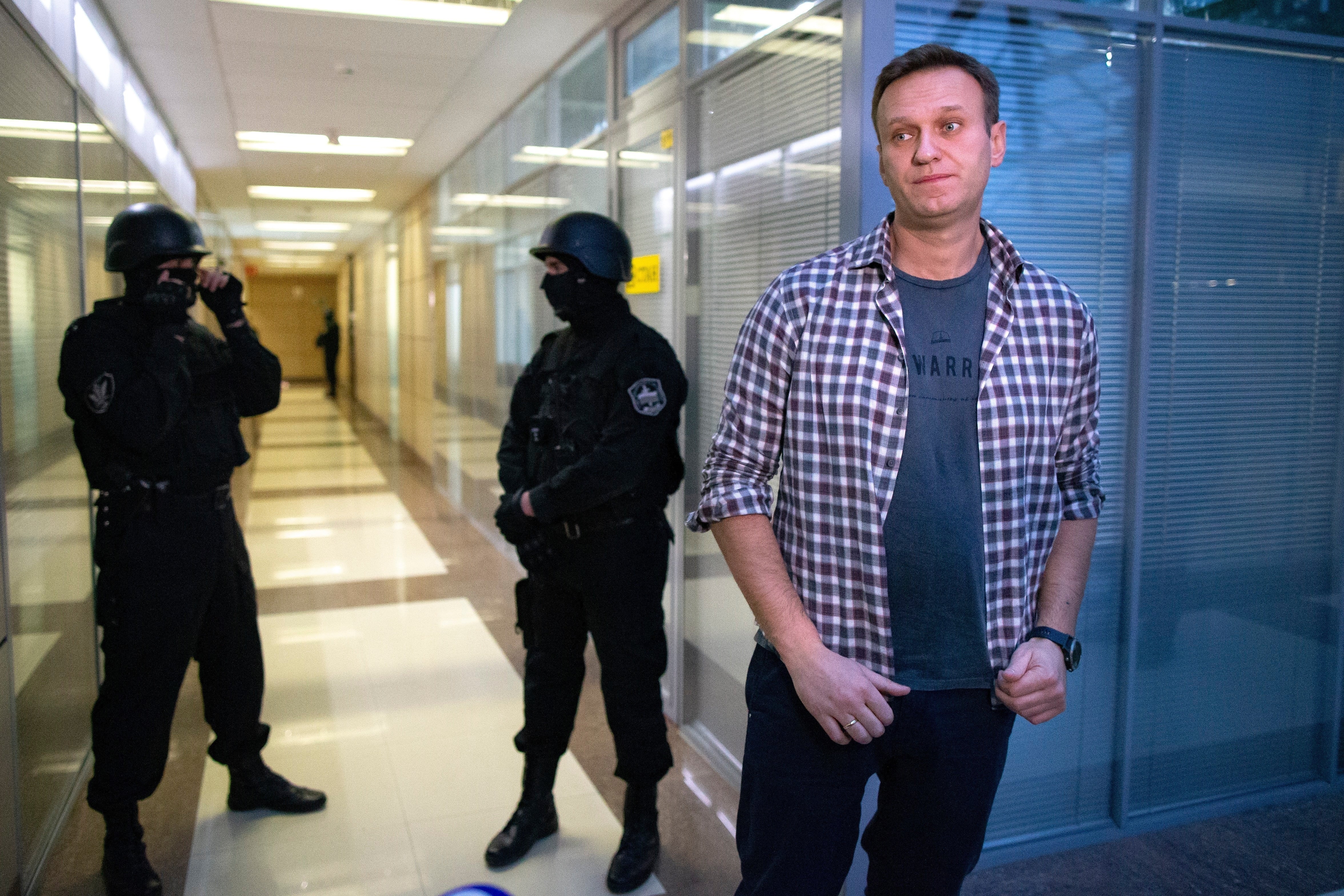 El líder opositor ruso Alexéi Navalny habla con los medios frente a agentes de seguridad que custodian la oficina de la Fundación para la Lucha contra la Corrupción en Moscú, Rusia, el jueves 26 de diciembre de 2019 (Foto AP/Alexander Zemlianichenko, Archivo)