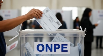 Una mano introduce una cédula en un ánfora transparente con el logo de ONPE. Varias personas borrosas se ven en el fondo de un centro de votación.