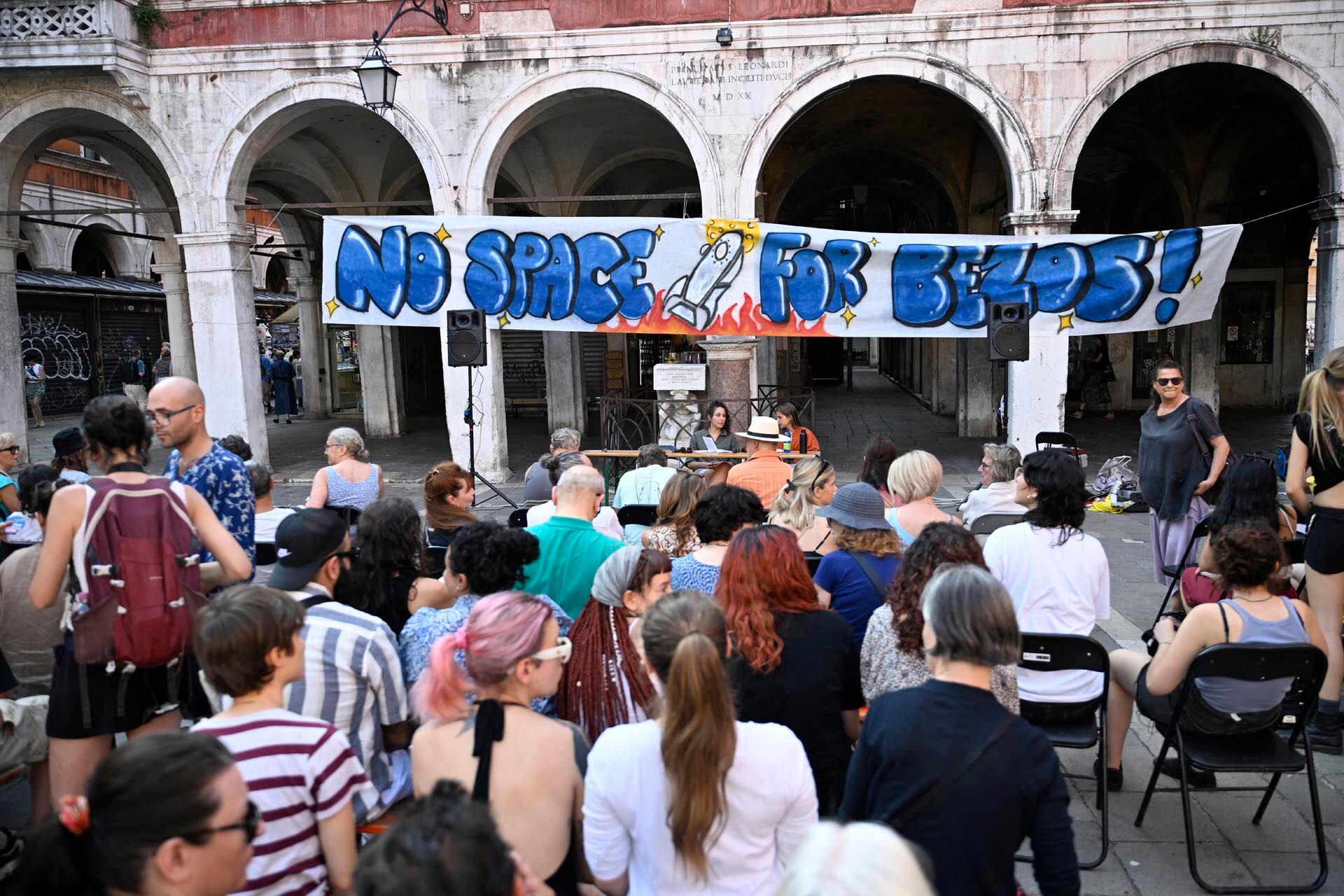 People gather to protest against the wedding of Amazon Founder and CEO Jeff Bezos and journalist Lauren Sanchez in Venice, on June 13, 2025. Poster campaigns and stickers have spread throughout the city, including one with images of Bezos reading