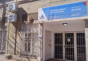 Fachada de un edificio con un cartel azul del Ministerio Público de la Acusación, Unidad Fiscal Melincué, y ventanas con rejas