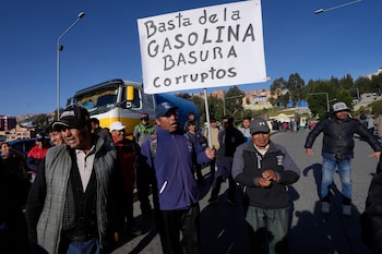 Conductores del transporte público protestan por la mala calidad de la gasolina; uno de ellos sostiene un cartel en el que se lee en español "Basta ya de gasolina basura. Corrupción", en La Paz, Bolivia, el miércoles 25 de marzo de 2026. (Foto AP/Juan Karita)