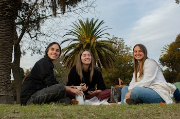 Tres jóvenes adultas disfrutan de un picnic al aire libre, creando un ambiente alegre y relajado (Pexels)