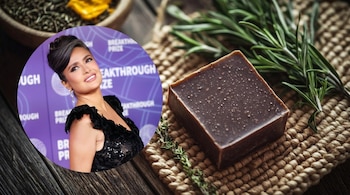 Salma Hayek en un círculo sobre fondo morado. Detrás, una barra de jabón marrón, romero, tomillo y una esterilla de yute sobre madera.