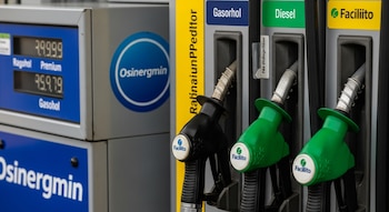 Primer plano de un surtidor de combustible moderno con una pantalla digital que muestra precios en soles, junto a boquillas y calcomanías de Osinergmin y Facilito.