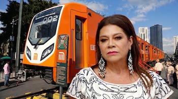 Una mujer de cabello castaño oscuro, con aretes largos y blusa bordada, de pie frente a un tren naranja brillante del Metro. Al fondo, se ven edificios urbanos.