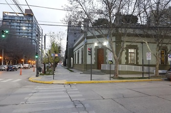 Intersección de calles, edificios, árboles, semáforos, vehículos, cables de luz, señales de tránsito, cruce peatonal
