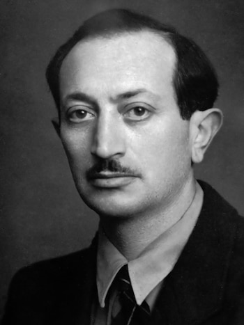 Retrato en blanco y negro de un hombre con bigote, camisa, corbata y chaqueta oscura sobre un fondo neutro